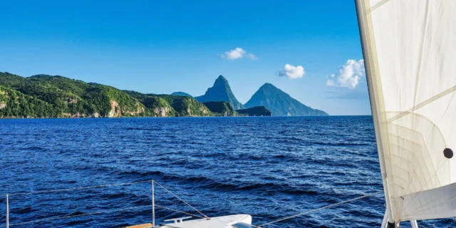 A boat sailing on the ocean with mountains in the background.