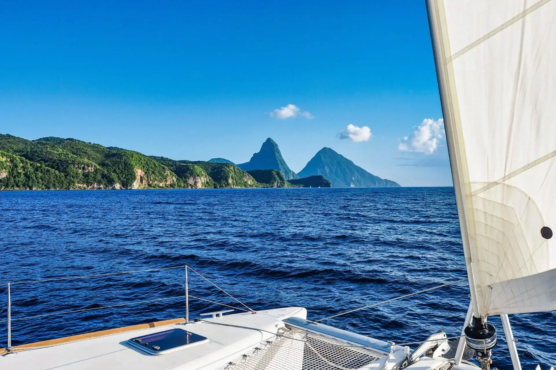 A boat sailing on the ocean with mountains in the background.