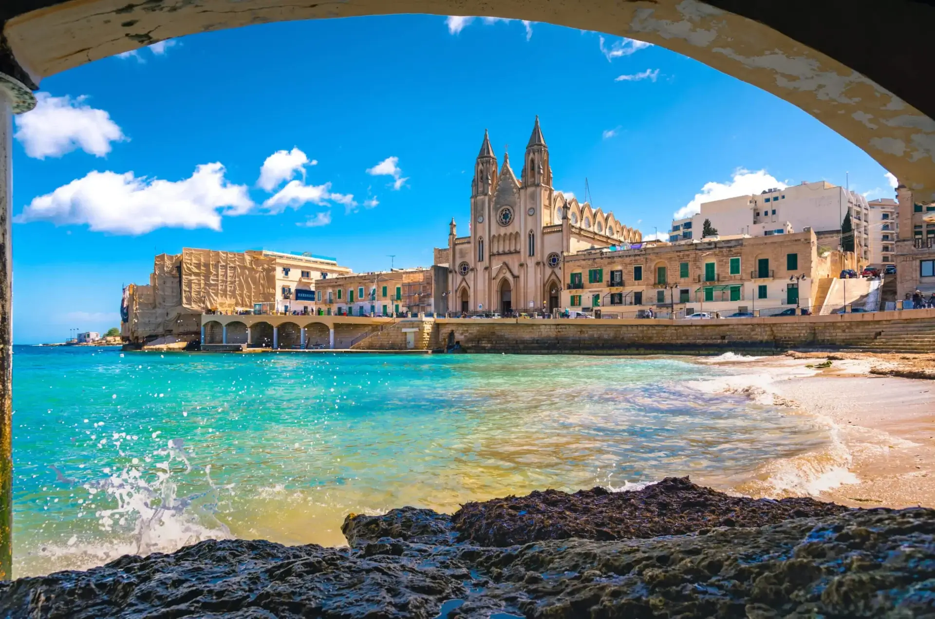 A view of the water and buildings from under an arch.